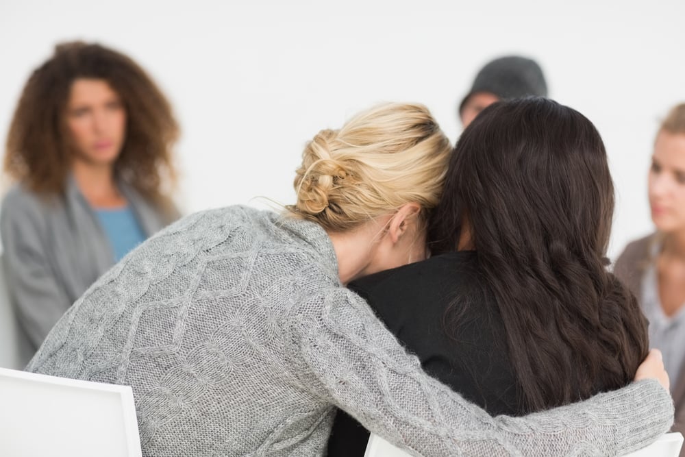 Women embracing in rehab group at therapy session