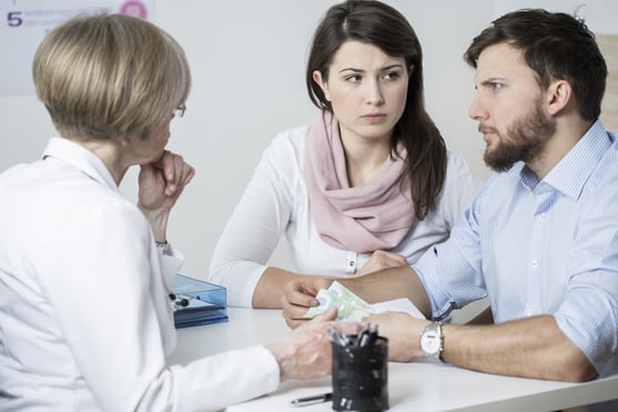 Young worried couple paying to experienced doctor for visit
