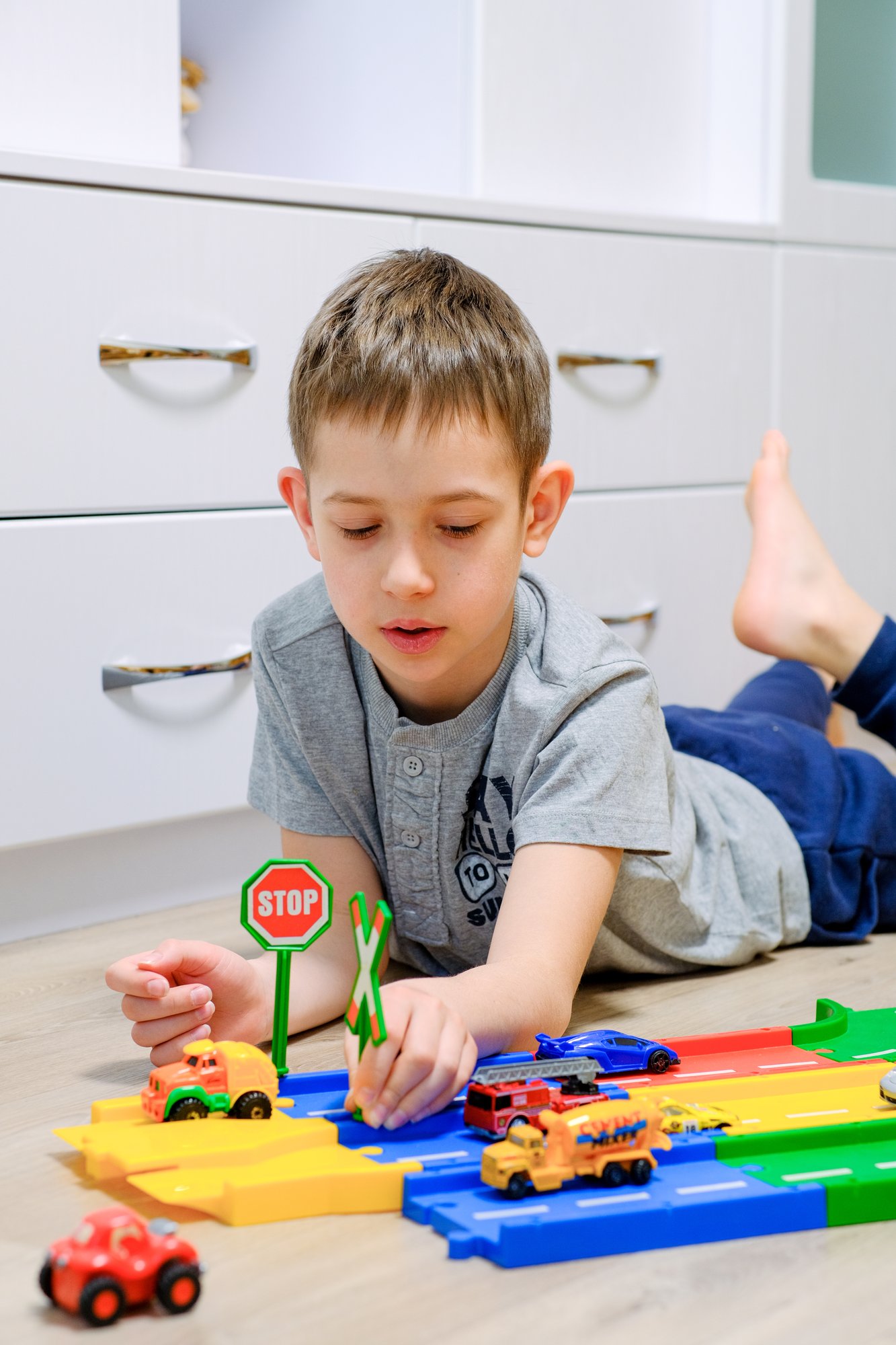 the-boy-plays-with-bright-multi-colored-cars-on-a-2022-11-16-09-05-52-utc